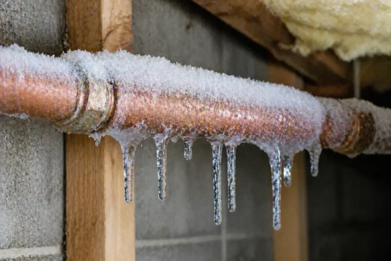 Copper pipe covered in frost and ice buildup in a cold basement area